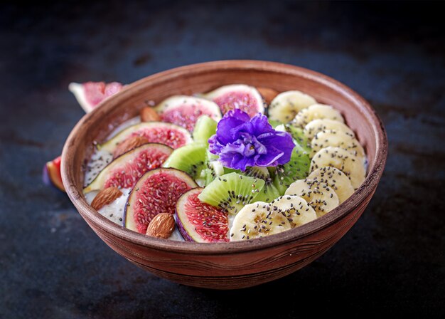 Deliciosa y saludable avena con higos, kiwi, plátano, almendras y semillas de chía. Mesa negra Desayuno saludable. Comida de fitness.