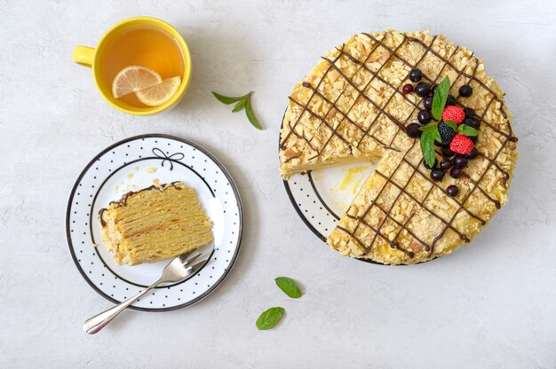 Deliciosa sobremesa festiva em camadas com massa folhada e creme decorado com frutas frescas e uma xícara de chá de limão