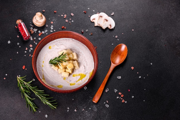 Deliciosa sopa de champiñones hermosa en un plato marrón con una cuchara de madera sobre un fondo marrón oscuro