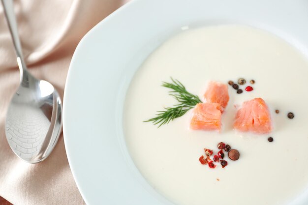 Deliciosa sopa de crema de salmón con cuchara en la mesa de madera de cerca