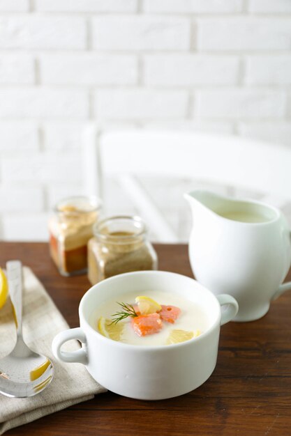 Foto deliciosa sopa de crema de salmón en una mesa de madera que se servía con limón en rodajas y especias