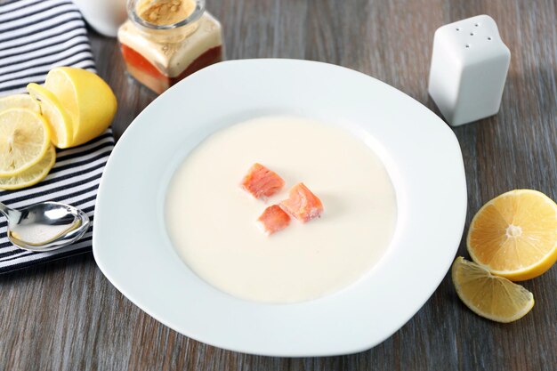 Deliciosa sopa de crema de salmón en un plato blanco sobre una mesa de madera de cerca