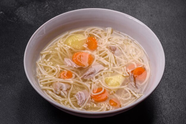 Deliciosa sopa con pollo de fideos y zanahorias con especias y hierbas sobre un fondo de hormigón oscuro