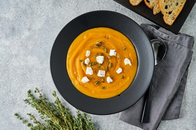 Deliciosa sopa de puré de crema de calabaza con queso feta, tostadas de tomillo y semillas