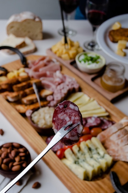 Foto deliciosa tabla de charcutería con bocadillos tostadas de queso tostadas de jamón y copas de vino tinto. concepto de comida