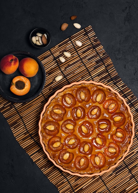 Deliciosa tarta de albaricoque dulce con nueces de almendra sobre fondo oscuro