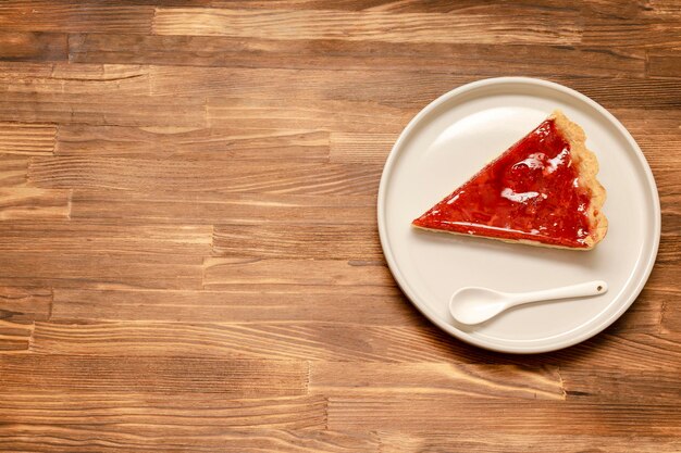 Deliciosa tarta de fresa y cereza roja y pastel desmoronado con una porción de postre de confección gourmet cubierto en un platoTarta de pastel de queso al horno con bayas maduras en una mesa de madera