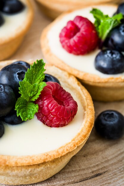 Deliciosa tartaleta con frambuesas y arándanos en la mesa de madera de cerca