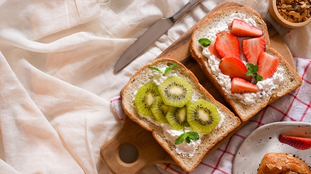 Deliciosa torrada de kiwi e morango com requeijão na placa de madeira e vista superior do espaço de cópia