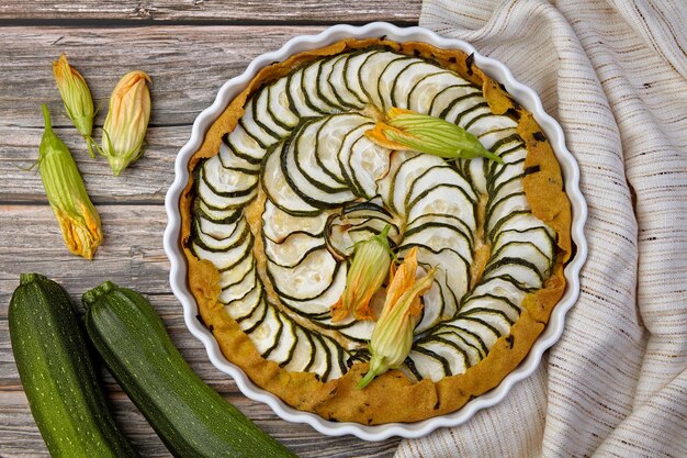 Deliciosa torta de abobrinha caseira com requeijão e ervas cercadas por sementes de flores e abobrinha