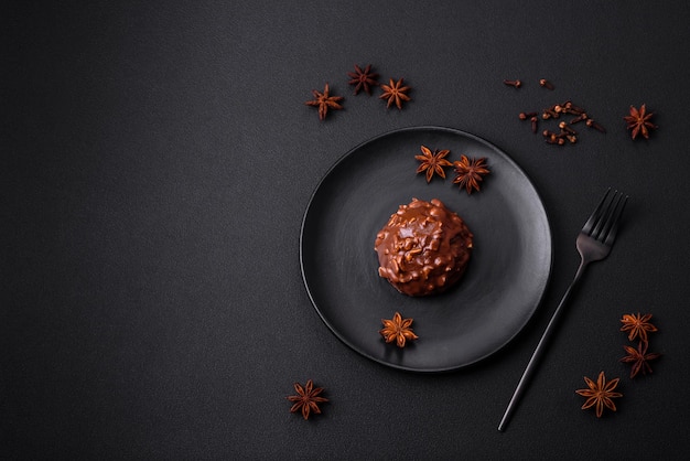 Deliciosa torta de chocolate com nozes em uma placa de cerâmica preta sobre um fundo escuro de concreto