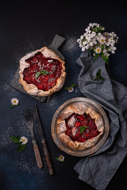 Deliciosa torta de morango de estilo rústico caseiro doce fresco com flores silvestres em fundo texturizado escuro