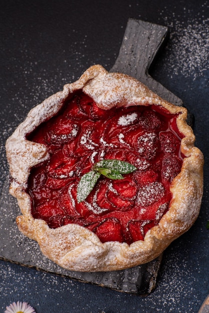 Deliciosa torta de morango de estilo rústico caseiro doce fresco com flores silvestres em fundo texturizado escuro