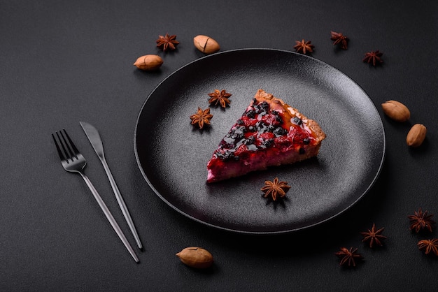 Deliciosa torta fresca com framboesas e outras frutas e queijo em um prato escuro sobre fundo preto