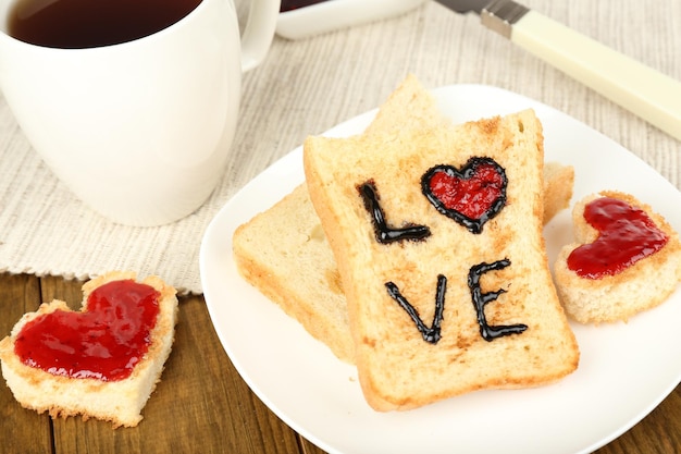 Deliciosa tostada con mermelada y taza de té en primer plano de la mesa