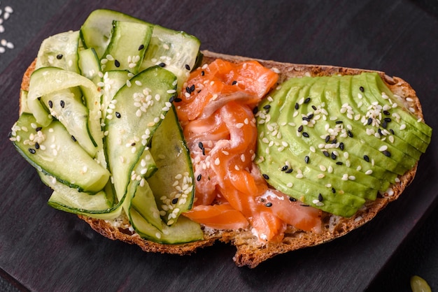 Deliciosa tostada de pan integral con salmón aguacate pepino y semillas de sésamo