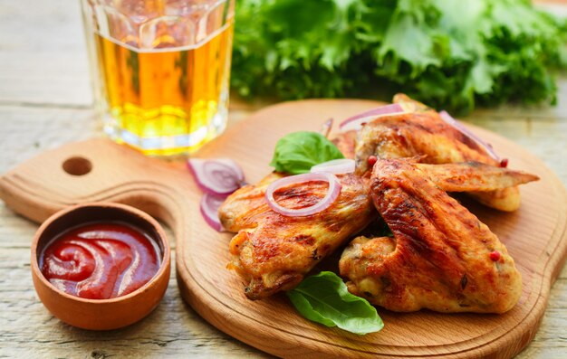 Deliciosas alitas de pollo fritas con especias, cebolla roja y salsa de tomate