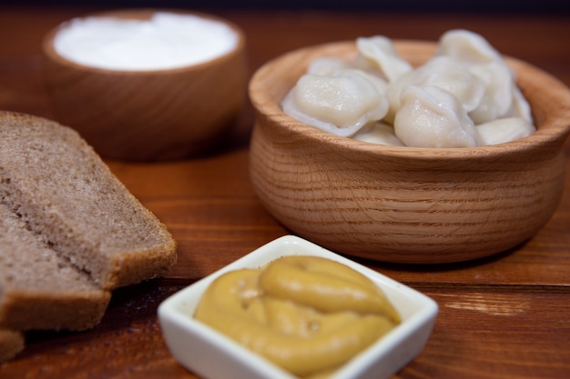 Deliciosas bolas de masa hervida sobre un fondo de madera con salsa de mostaza, crema agria y pan.