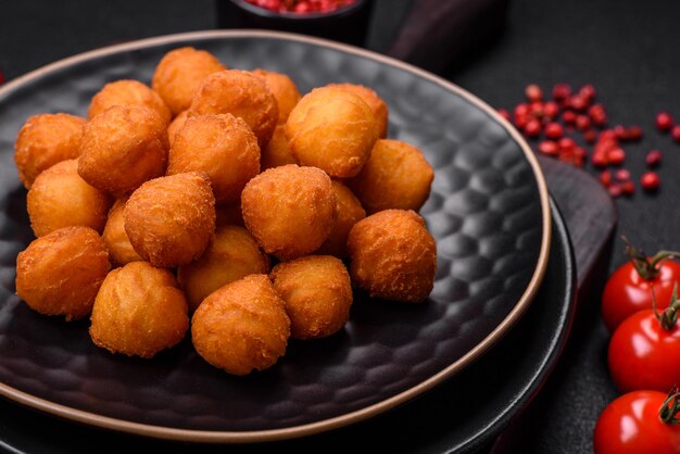 Deliciosas bolas de patatas fritas con especias de sal de mozzarella en pan y hierbas sobre un fondo de hormigón oscuro