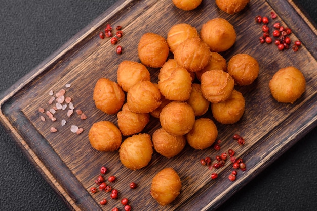 Deliciosas bolas de patatas fritas con especias de sal de mozzarella en pan y hierbas sobre un fondo de hormigón oscuro