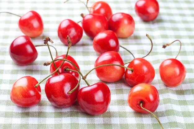 Deliciosas cerezas maduras esparcidas sobre tela escocesa