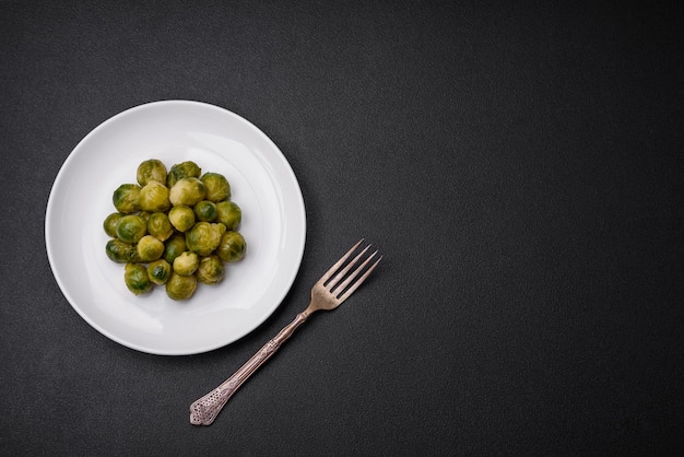 Deliciosas coles de Bruselas hervidas en un plato de cerámica sobre un fondo de hormigón oscuro