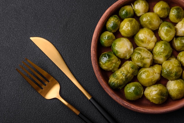 Deliciosas coles de Bruselas hervidas en un plato de cerámica sobre un fondo de hormigón oscuro