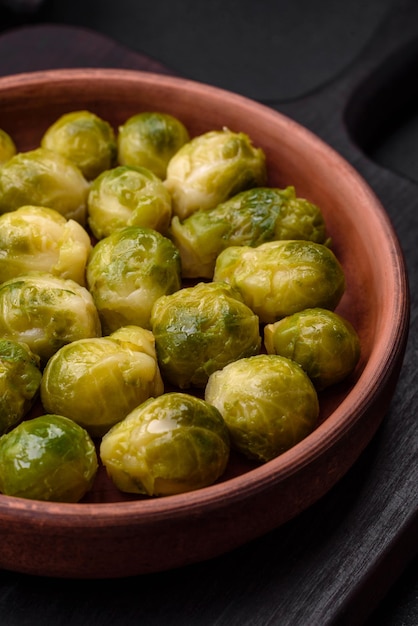 Deliciosas coles de Bruselas hervidas en un plato de cerámica sobre un fondo de hormigón oscuro