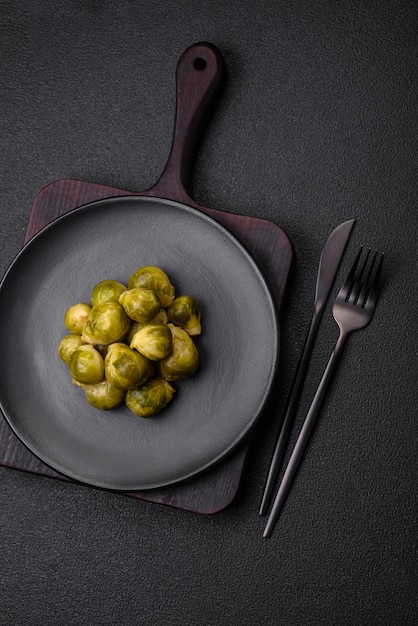 Deliciosas couves de Bruxelas cozidas num prato cerâmico sobre um fundo escuro de concreto Comida vegetariana