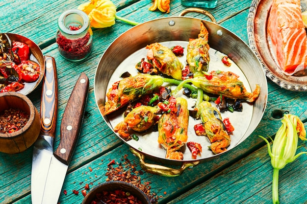 Deliciosas flores de abobrinha fritas recheadas com tomates secos ao sol. Comida de verão.