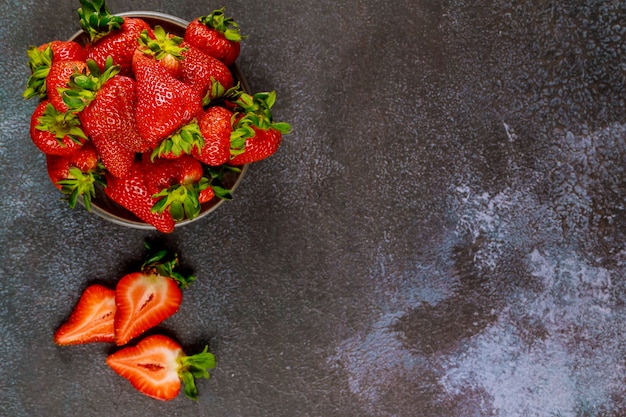 Deliciosas fresas maduras en un plato sobre una superficie gris