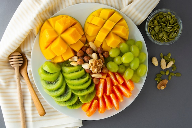 Deliciosas frutas platte con: mango, kiwi, cítricos, nueces, uvas. Mezcla de varias frutas exóticas