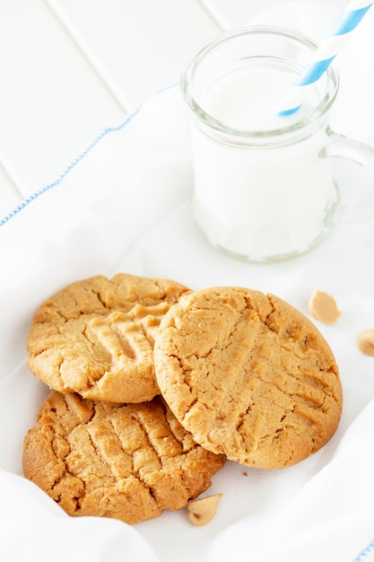 Foto deliciosas galletas de mantequilla de maní caseras con taza de leche. espacio de madera blanca. merienda saludable o sabroso desayuno concepto.