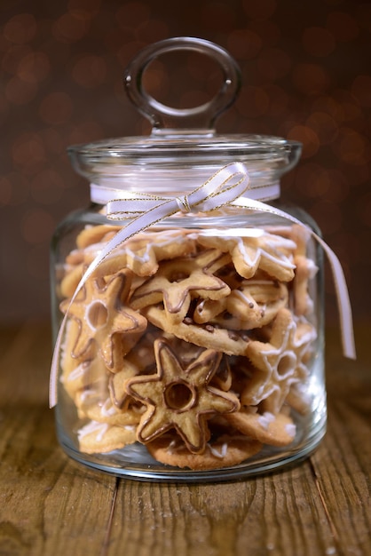 Deliciosas galletas de Navidad en el tarro en la mesa sobre fondo marrón