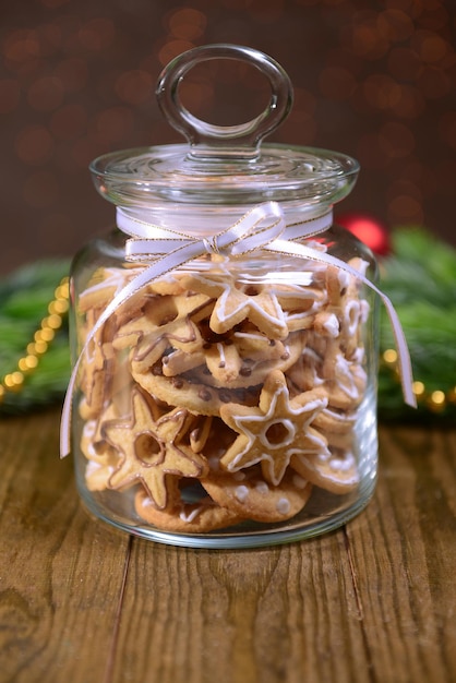 Deliciosas galletas de Navidad en el tarro en la mesa sobre fondo marrón