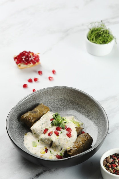 Deliciosas hojas de parra rellenas de doom tradicional cocina mediterránea Dolma con fruta de granada sobre fondo de mármol.