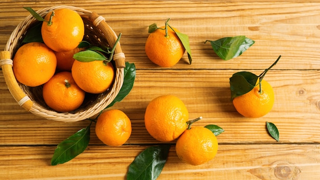 Deliciosas mandarinas maduras brillantes con hojas sobre una mesa de madera