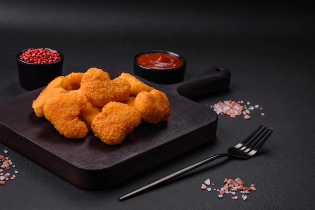 Deliciosas nuggets de frango frescas e crocantes sobre um fundo de concreto escuro