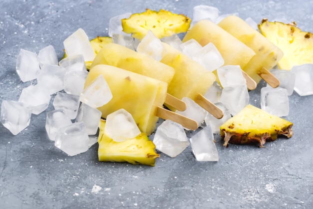 Deliciosas paletas de piña caseras en cubos de hielo fondo gris concepto de comida de verano por encima de la horizontal