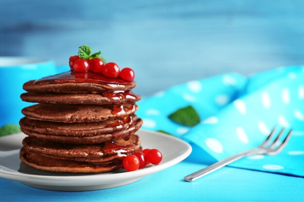 Deliciosas panquecas de chocolate com viburnum na mesa de madeira azul