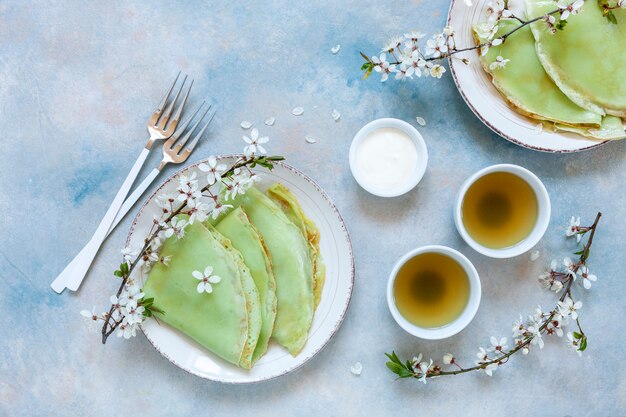 Deliciosas panquecas verdes caseiras com galhos de árvores de cereja em flor com chá verde