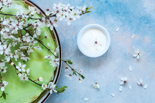 Deliciosas panquecas verdes caseiras com galhos de árvores de cereja em flor