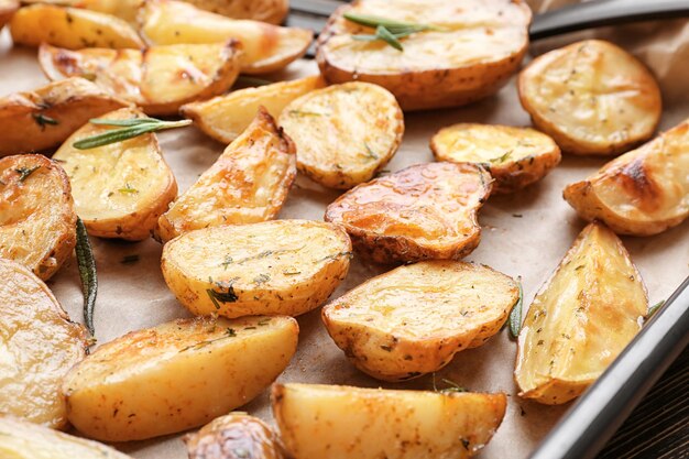 Deliciosas papas al horno con romero en la bandeja para hornear closeup