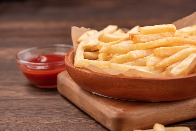 Deliciosas papas fritas doradas sobre papel kraft para hornear y bandeja para comer con salsa de tomate y mostaza amarilla, cerca, estilo de vida.