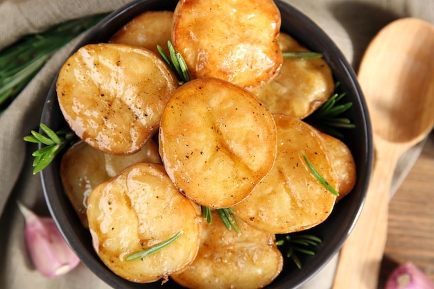 Deliciosas patatas al horno con romero en un tazón en la mesa de cerca