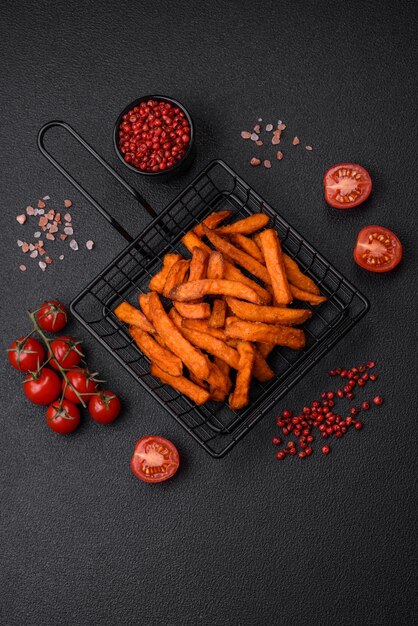 Deliciosas patatas fritas crujientes con especias saladas y hierbas sobre un fondo de hormigón oscuro