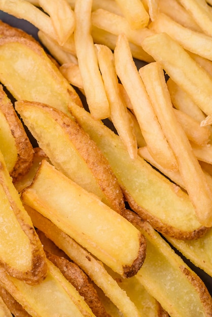 Deliciosas patatas fritas crujientes con sal y especias sobre un fondo de hormigón con textura comida rápida