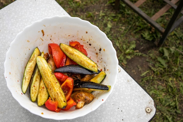 Deliciosas rebanadas de verduras a la parrilla con fondo rústico césped y barbacoa