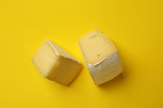 Deliciosas rodajas de queso camembert sobre fondo amarillo, cerrar