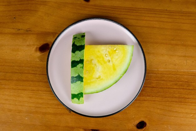 Deliciosas rodajas de sandía amarilla servida en un plato de luz sobre una mesa con fondo de madera